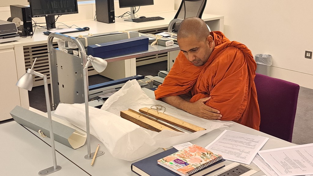 Venerable Kothmale Kumarakassapa Thero studying a Sinhala palm leaf manuscript in the Wellcome Collection Rare Materials Room.